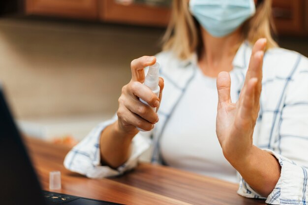 Donna a casa durante la quarantena la spruzzatura di disinfettante per le mani sulle mani