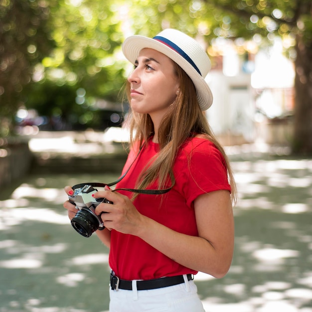 Donna a metà colpo con cappello e macchina fotografica