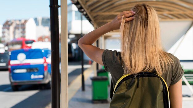 Donna a metà tiro con lo zaino nella stazione degli autobus