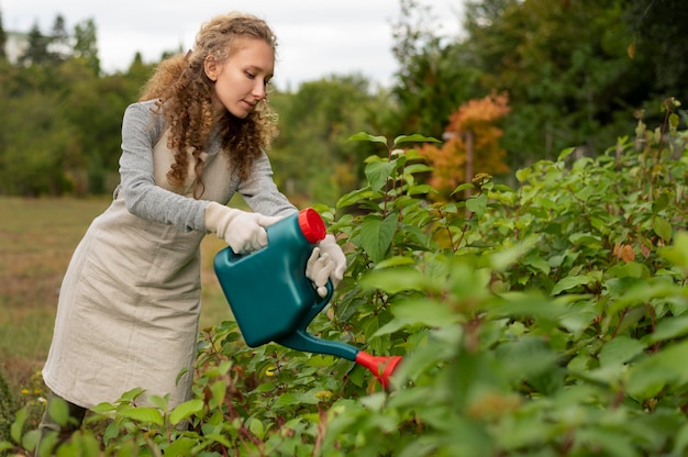 Donna a tiro medio che innaffia la vegetazione