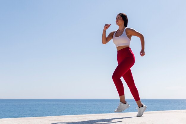 Donna a tutto campo che corre in riva al mare