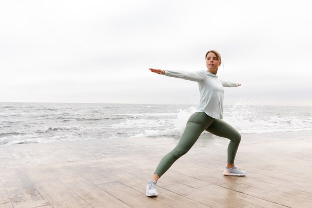 Donna a tutto campo che fa yoga in spiaggia?