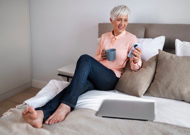 Donna a tutto campo che si prende una pausa con lo smartphone