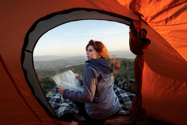 Donna a tutto campo seduta vicino alla tenda