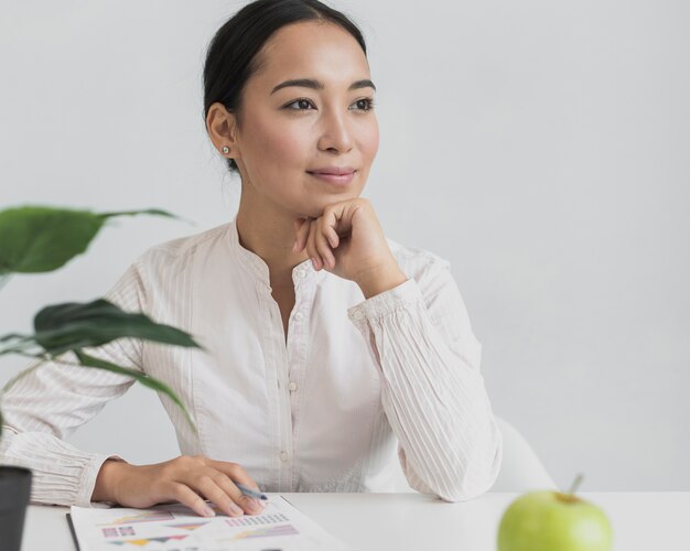 Donna abbastanza asiatica che si siede nel suo ufficio