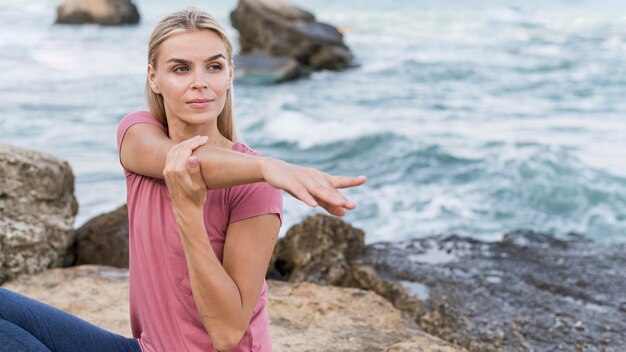 Donna abbastanza bionda che si estende in spiaggia