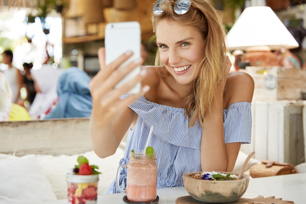 Donna abbastanza bionda che si siede nella caffetteria