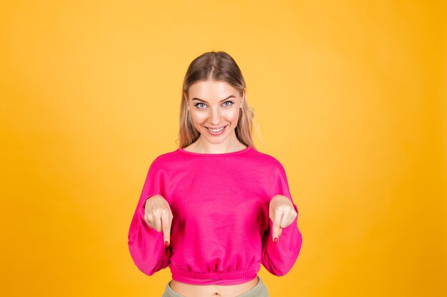 Donna abbastanza europea in camicetta rosa sulla parete gialla