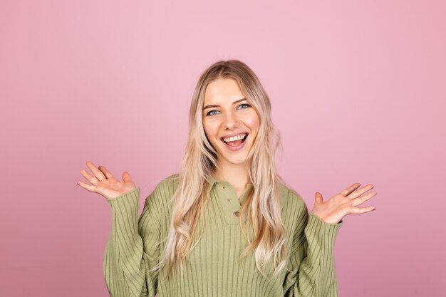 Donna abbastanza europea in maglione lavorato a maglia casual sulla parete rosa