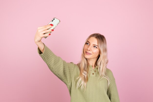 Donna abbastanza europea in maglione lavorato a maglia casual sulla parete rosa