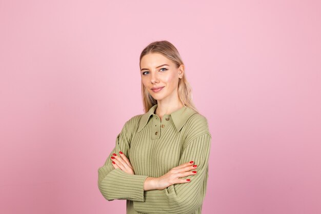 Donna abbastanza europea in maglione lavorato a maglia casual sulla parete rosa