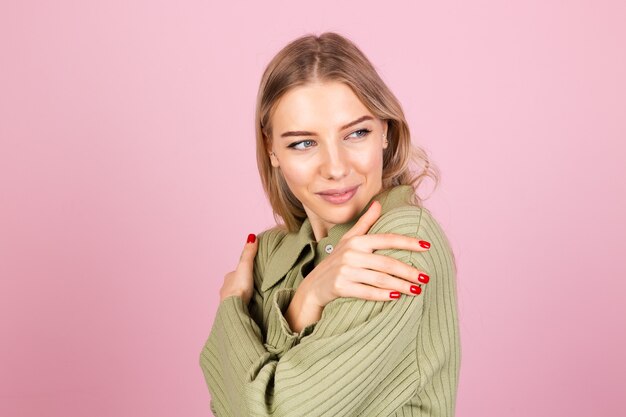 Donna abbastanza europea in maglione lavorato a maglia casual sulla parete rosa