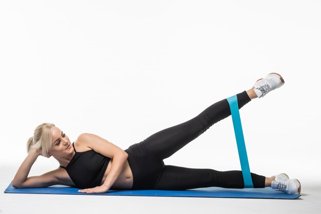 Donna abbastanza forte che fa esercizi di stretching sul pavimento in studio su bianco