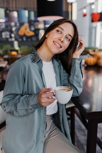 Donna abbastanza giovane che gode di una tazza di caffè