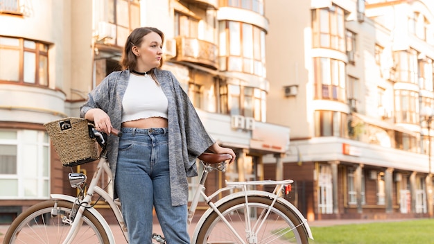 Donna abbastanza giovane che posa con la bici