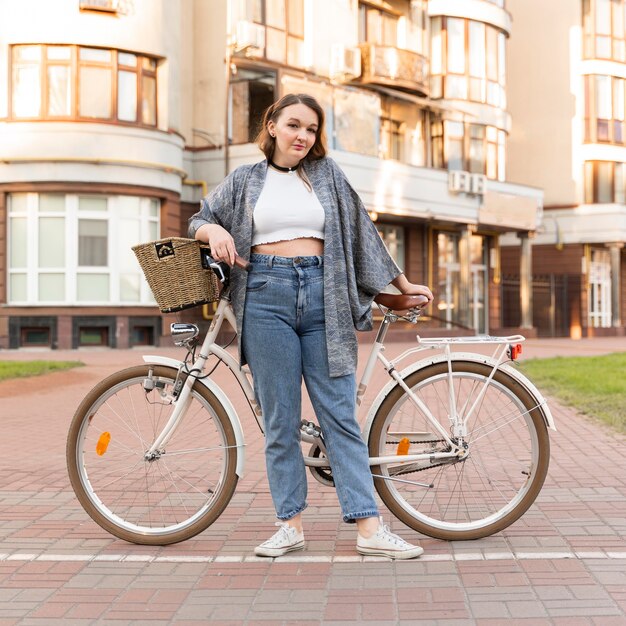 Donna abbastanza giovane che posa con la bici