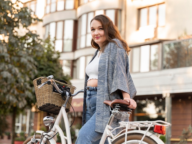 Donna abbastanza giovane che posa con la bici