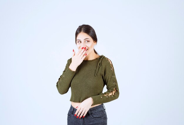 Donna abbastanza sorridente che copre la bocca sul muro bianco