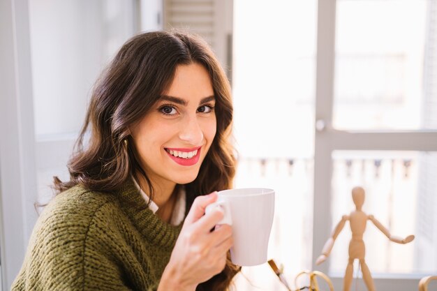 Donna adorabile con la tazza che guarda l&#39;obbiettivo