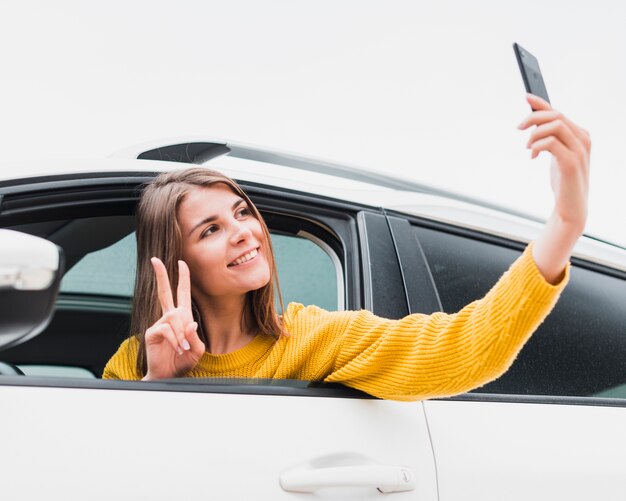 Donna adorabile in automobile che prende un selfie