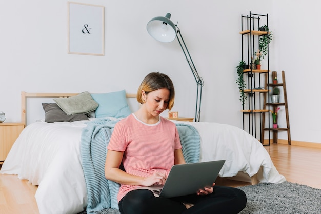 Donna adulta che utilizza computer portatile sul pavimento