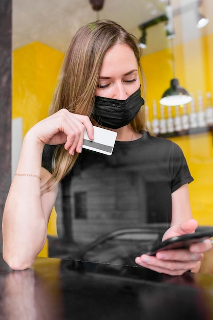 Donna adulta con la maschera di protezione che compera online