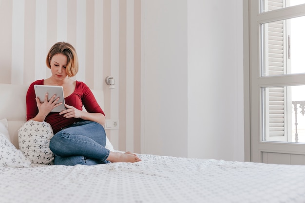 Donna adulta con tavoletta sul letto