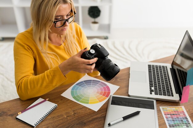 Donna adulta graziosa che controlla macchina fotografica professionale