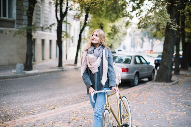 Donna affascinante che cammina con la bicicletta