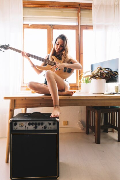 Donna affascinante che gioca chitarra sul tavolo