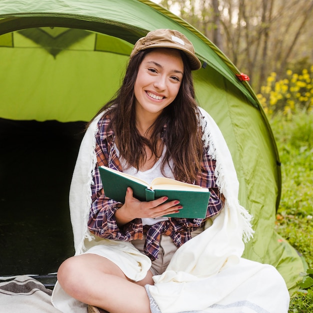 Donna affascinante con il libro vicino alla tenda