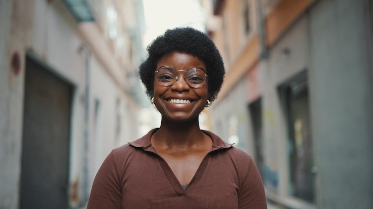 Foto gratuito donna africana allegra in vetri che sembra felice all'aperto carefr