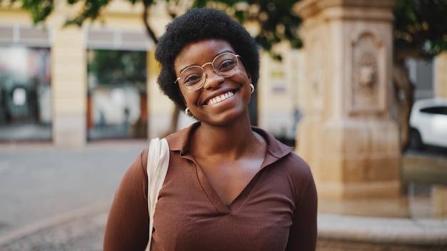 Donna africana allegra in vetri che sembra sorridente felice al camer