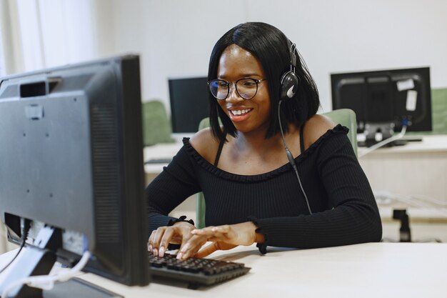 Donna africana che si siede nella classe di informatica. Signora con gli occhiali. Studentessa seduta al computer.