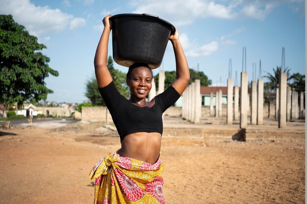 Donna africana con un secchio d'acqua in testa