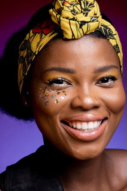 Donna africana di smiley in giubbotto di pelle con coriandoli lucidi sulle guance