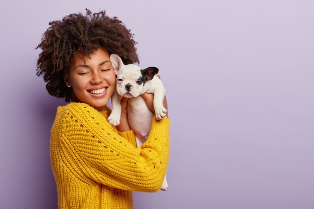 Donna afro-americana che indossa un maglione giallo che tiene cucciolo