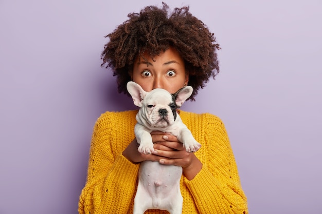 Donna afro-americana che indossa un maglione giallo che tiene cucciolo