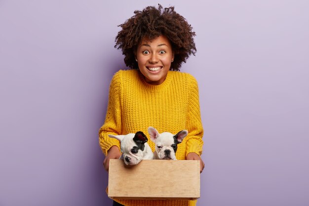 Donna afro-americana che indossa un maglione giallo che tiene i cuccioli