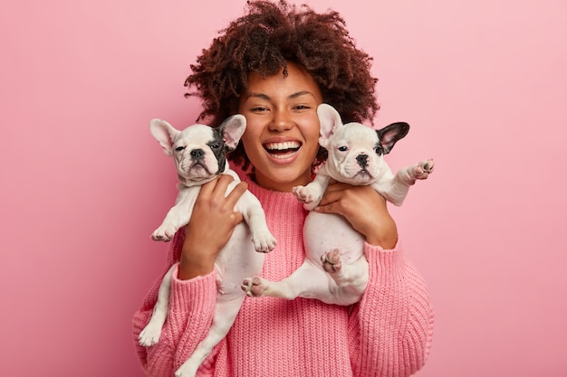 Donna afro-americana che indossa un maglione rosa che tiene i cuccioli