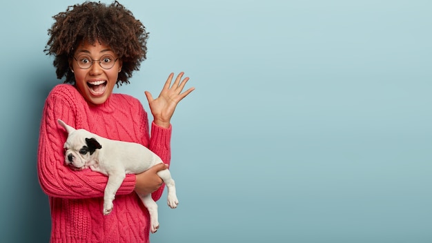 Donna afro-americana che indossa un maglione rosa tenendo il cane