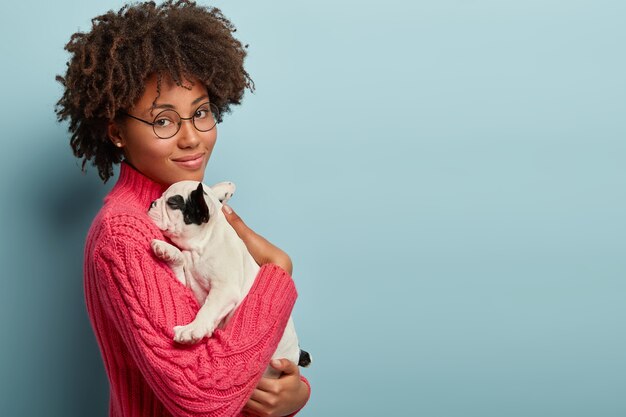 Donna afro-americana che indossa un maglione rosa tenendo il cane