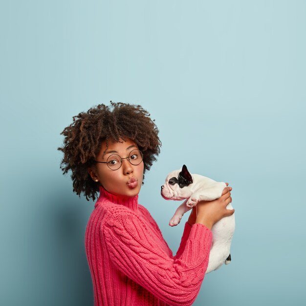 Donna afro-americana che indossa un maglione rosa tenendo il cane