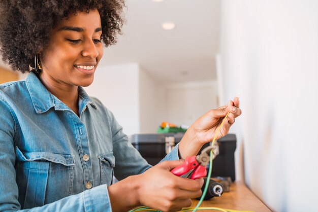 Donna afro che ripara problema di elettricità a casa.