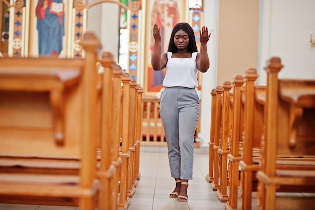 Donna afroamericana che prega nella chiesa I credenti meditano nella cattedrale e il tempo spirituale della preghiera La ragazza afro tiene le mani in alto