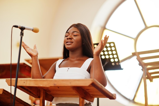 Donna afroamericana che prega nella chiesa I credenti meditano nella cattedrale e nel tempo spirituale della preghiera Ragazza afro che canta e glorifica Dio sui cori