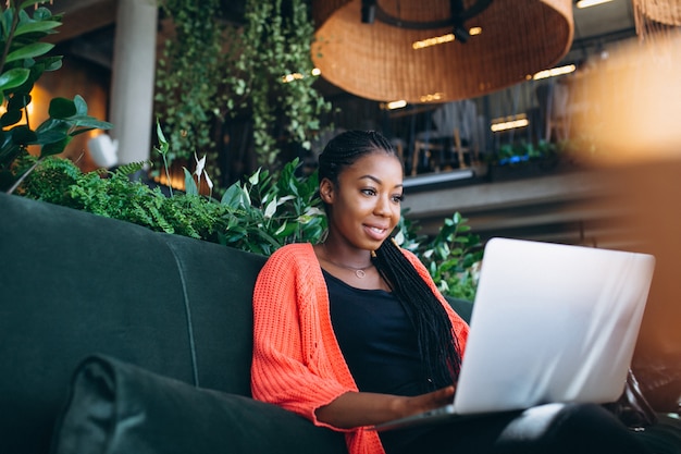 Donna afroamericana con il computer portatile in un caffè