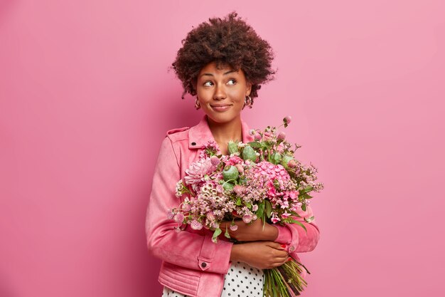 Donna afroamericana pensierosa con un bel mazzo di fiori, vestita con abiti alla moda,