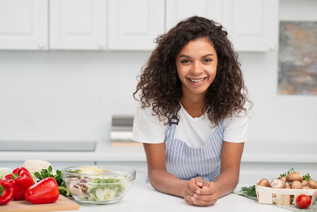 Donna afroamericana sorridente che posa accanto alle verdure