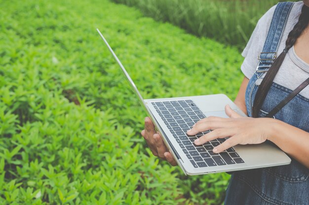 Donna agricola che ispeziona la pianta con compresse coltivate - un concetto moderno